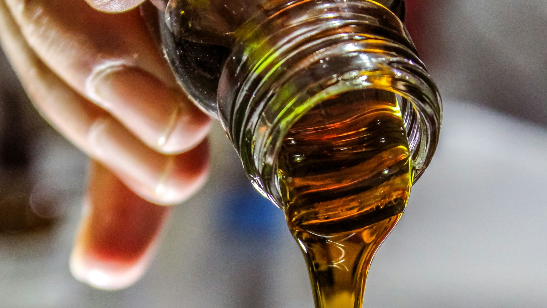 person holding clear drinking glass with brown liquid
