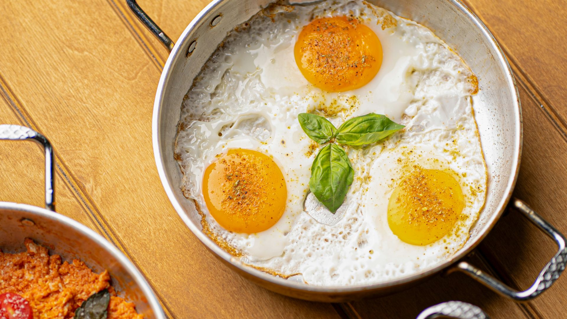 Three pans of breakfast food on wooden table