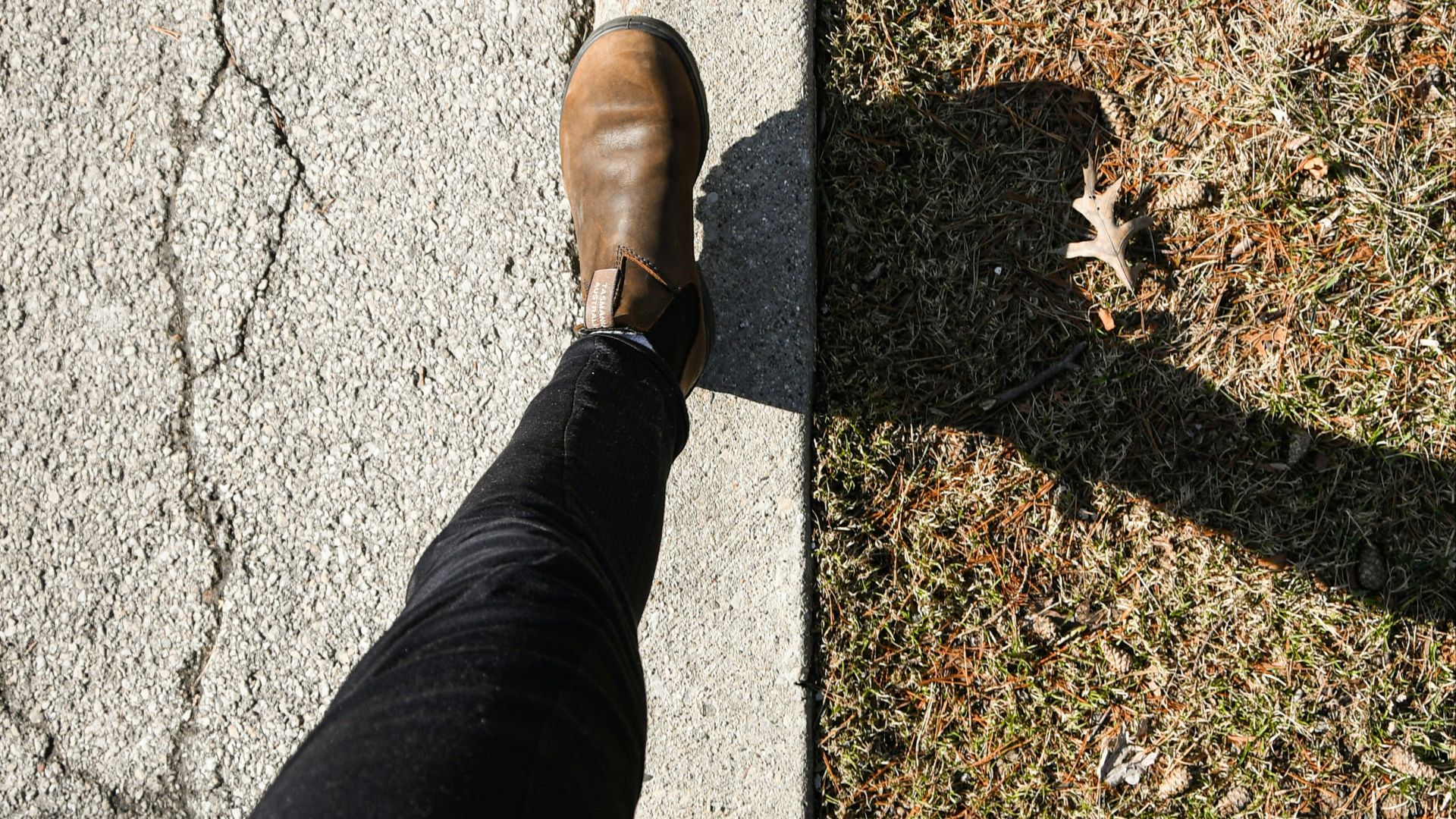 a person standing on a sidewalk with their feet on the ground