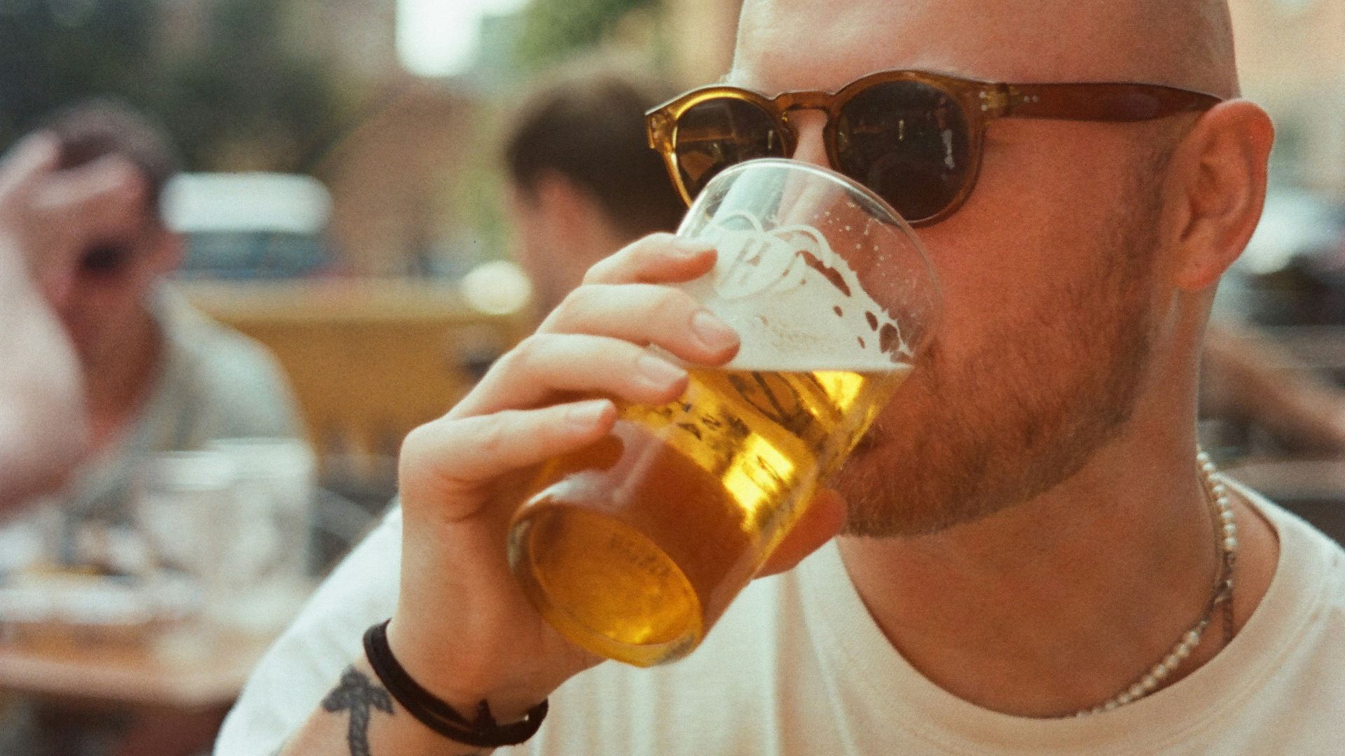 a man with a bald head drinking a beer