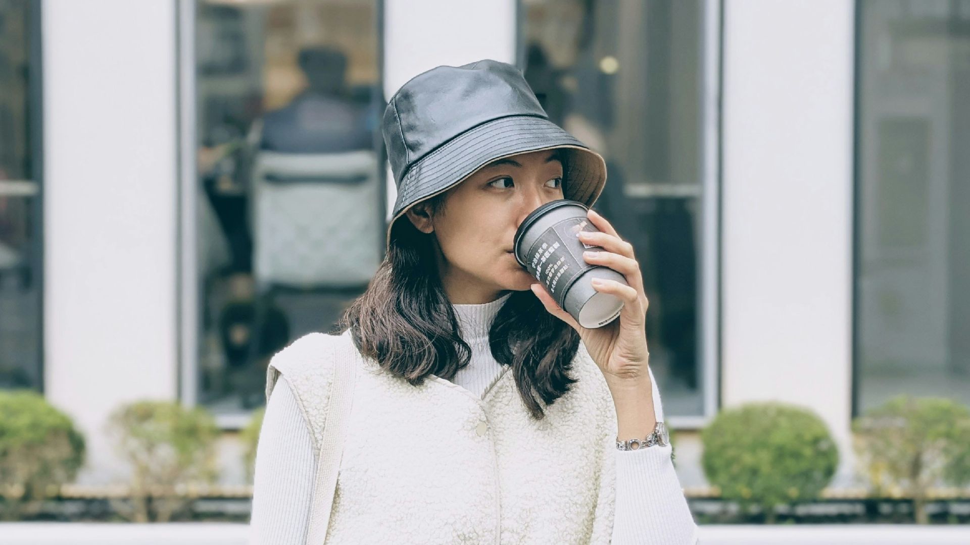 woman in white sweater wearing black cap holding black dslr camera