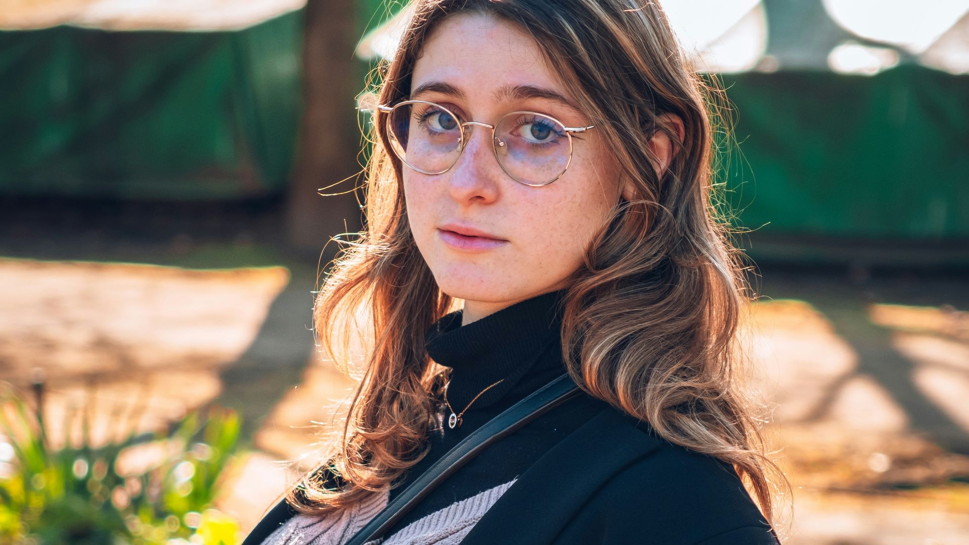 a woman wearing glasses sitting on a green chair