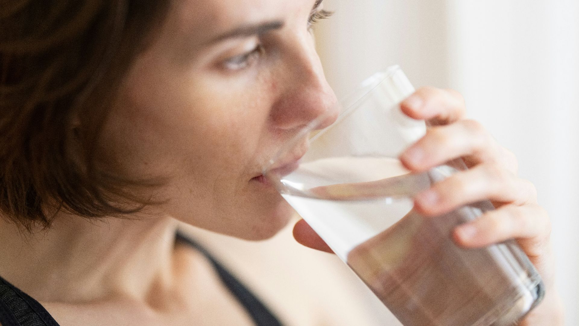 woman in black tank top drinking water