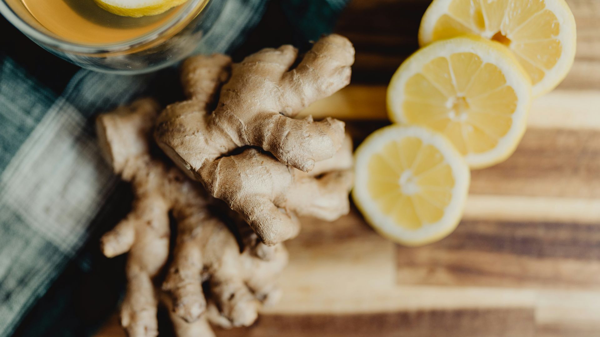 a glass of orange juice next to sliced lemons and ginger