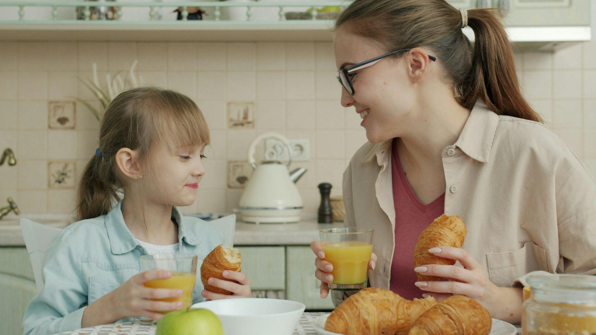 Mother and daughter enjoying breakfast with croissants.