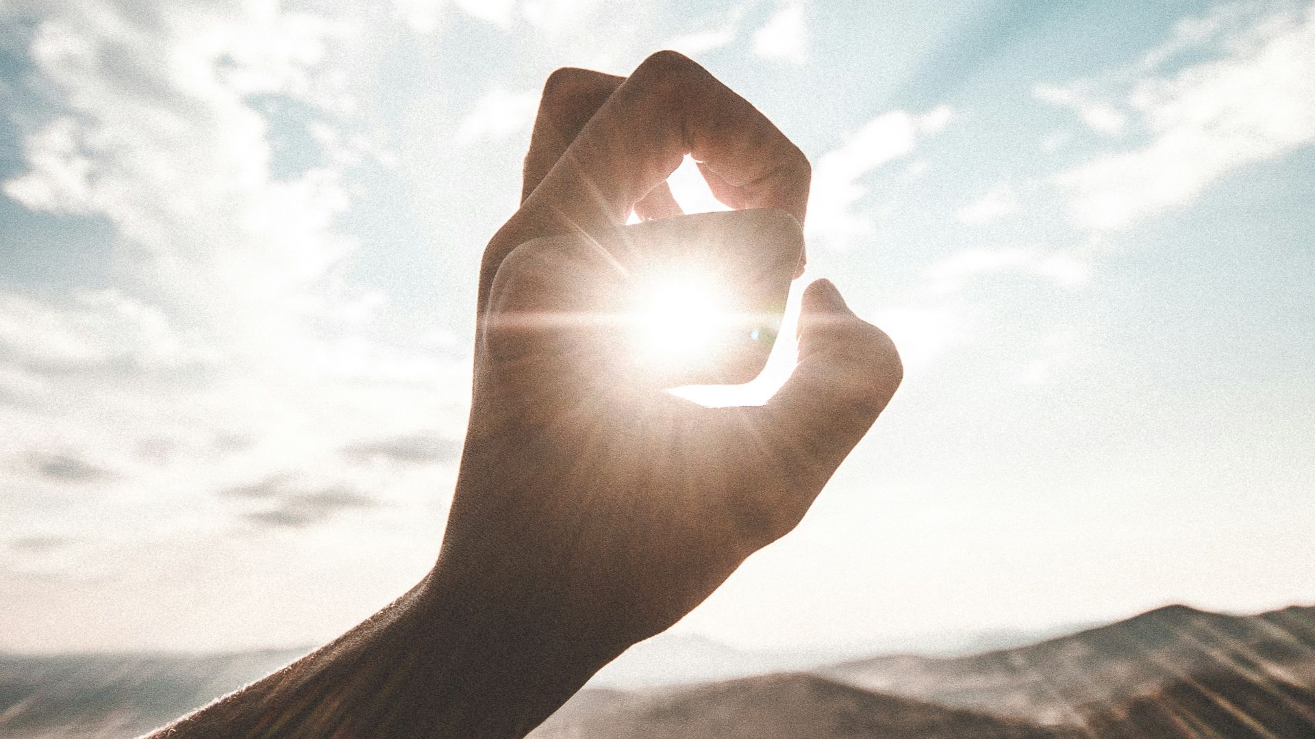 photography of sun glaring through the hole of finger