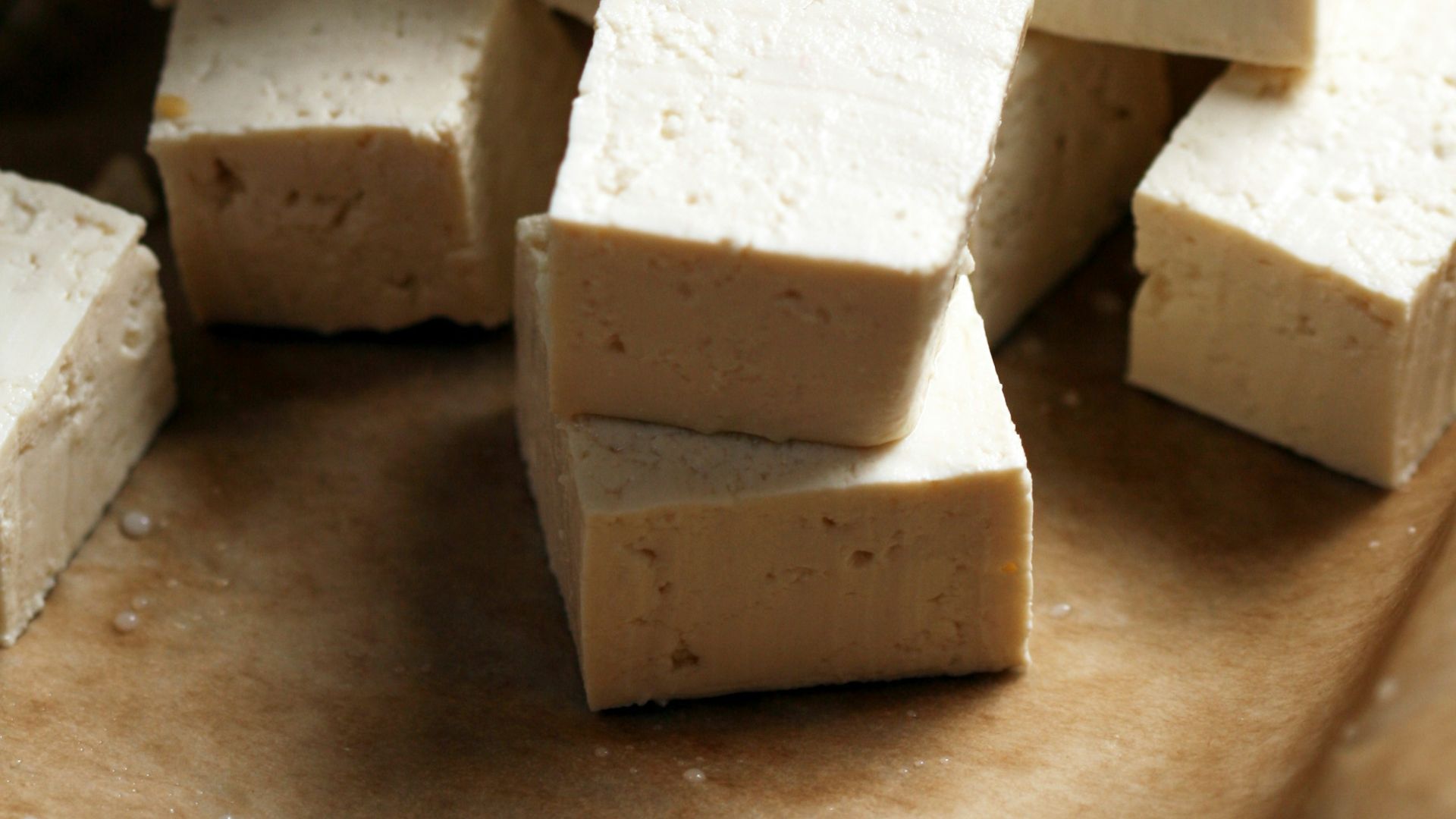A pile of tofu cubes sitting on top of a cutting board