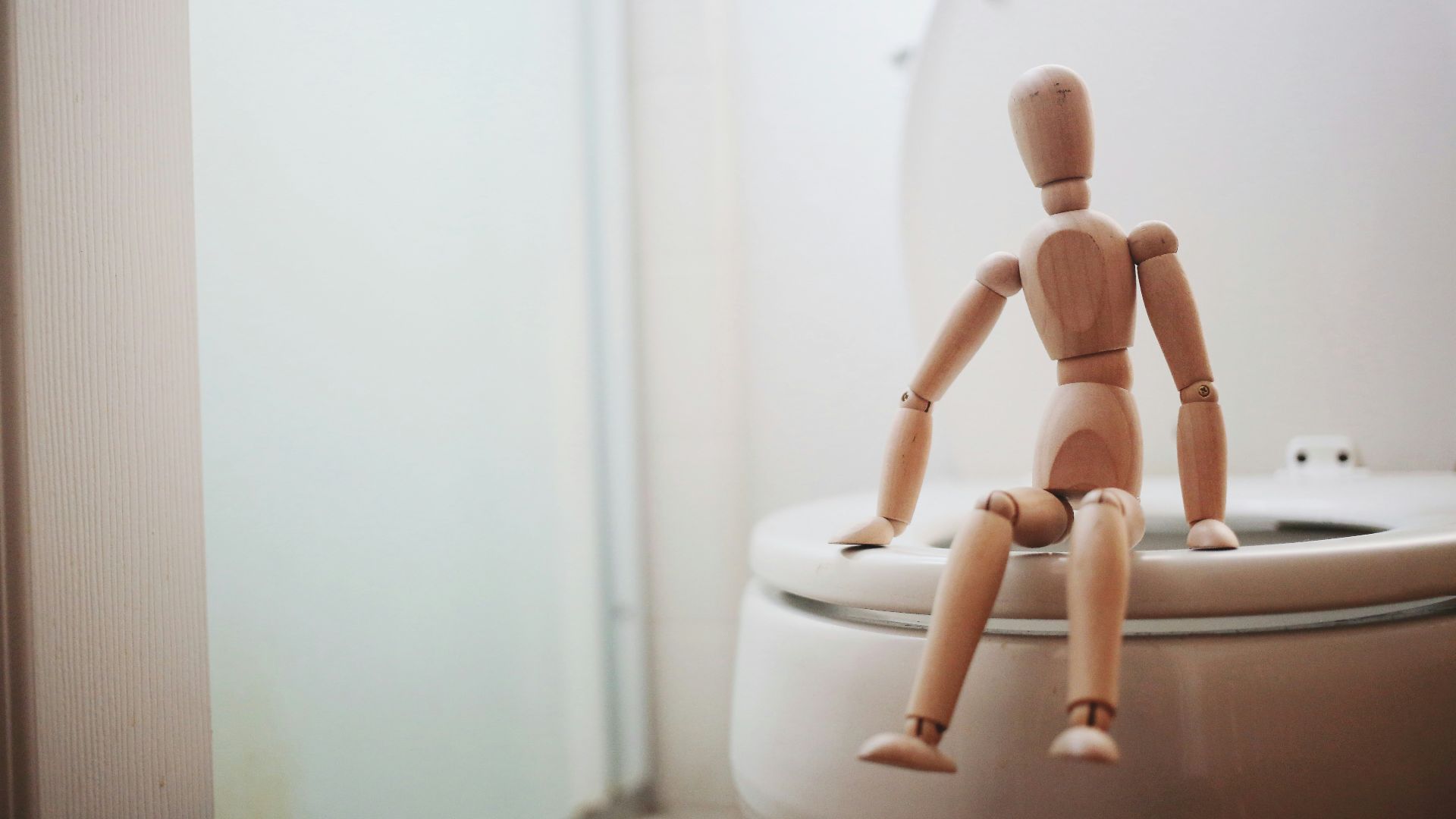 brown wooden doll on white ceramic toilet bowl