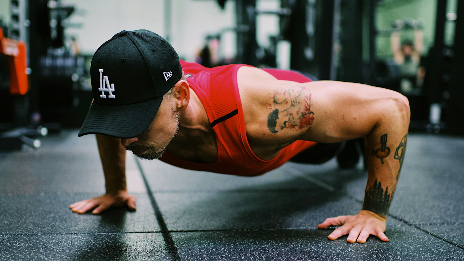 woman in red sports bra and black shorts doing push up on gray concrete road during