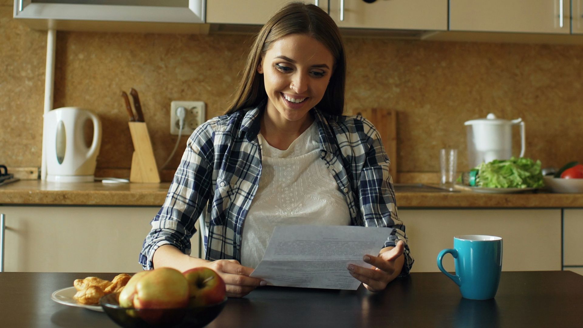 Woman reading document at kitchen table with coffee