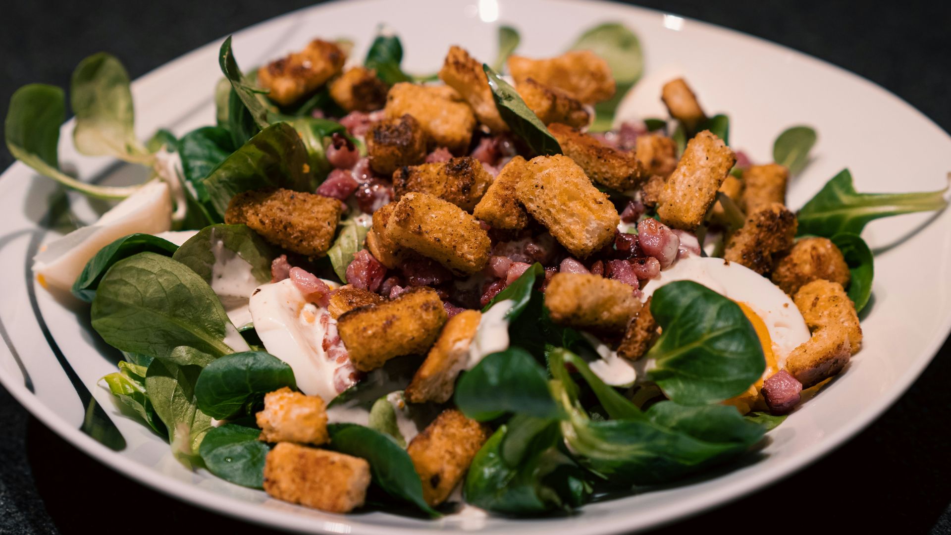 a white plate topped with a salad covered in croutons