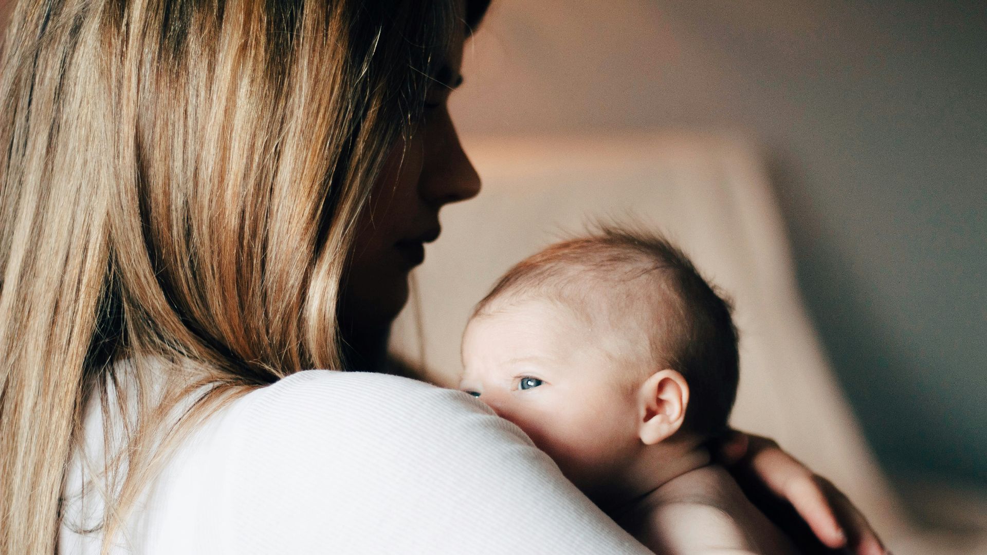 woman in white shirt carrying baby