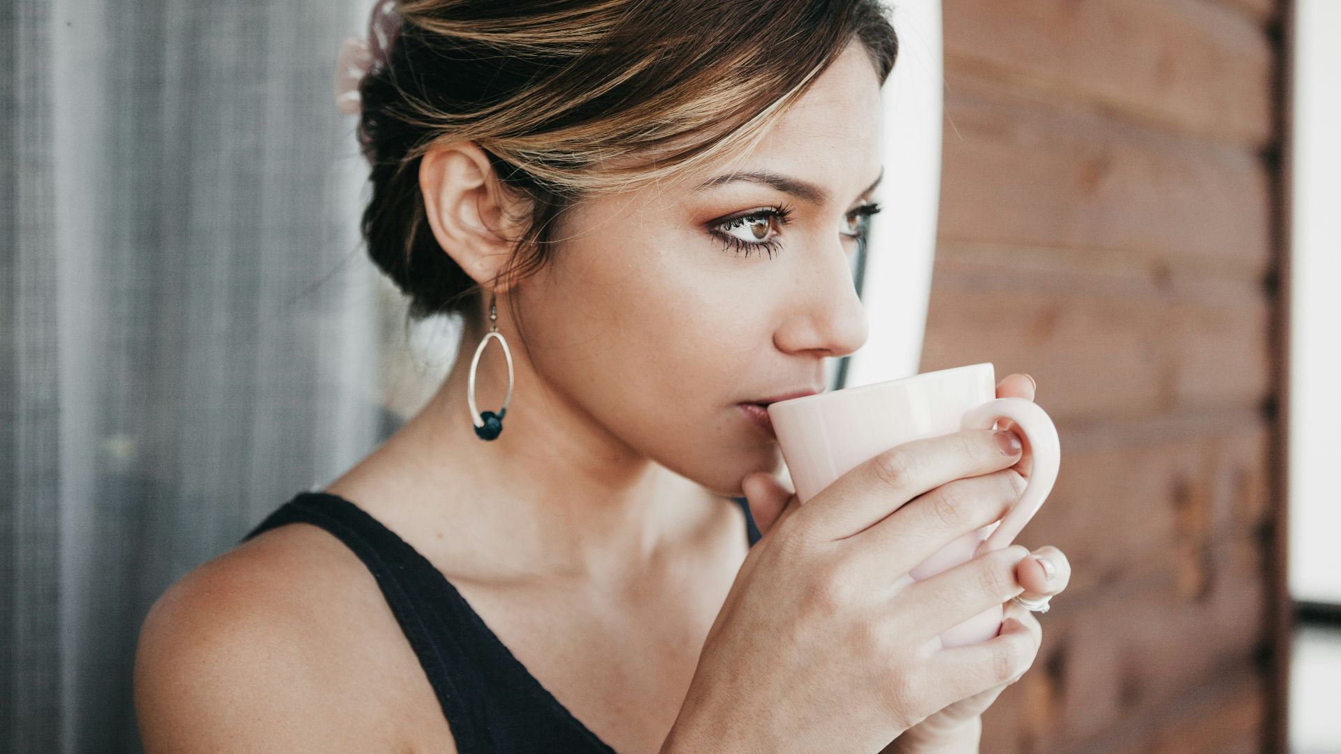 woman leaning on wall drinking coffee