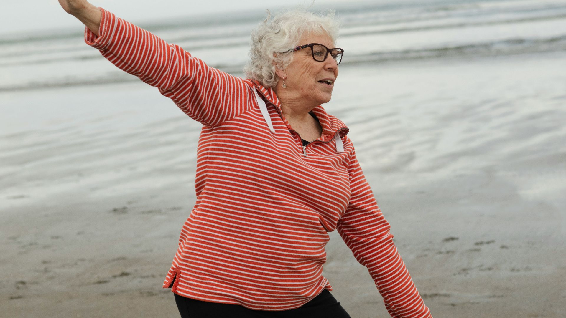 Woman practices tai chi on the beach.