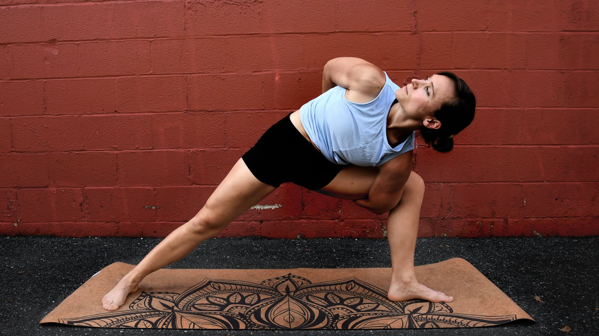 woman in white tank top and black shorts doing yoga on brown concrete floor