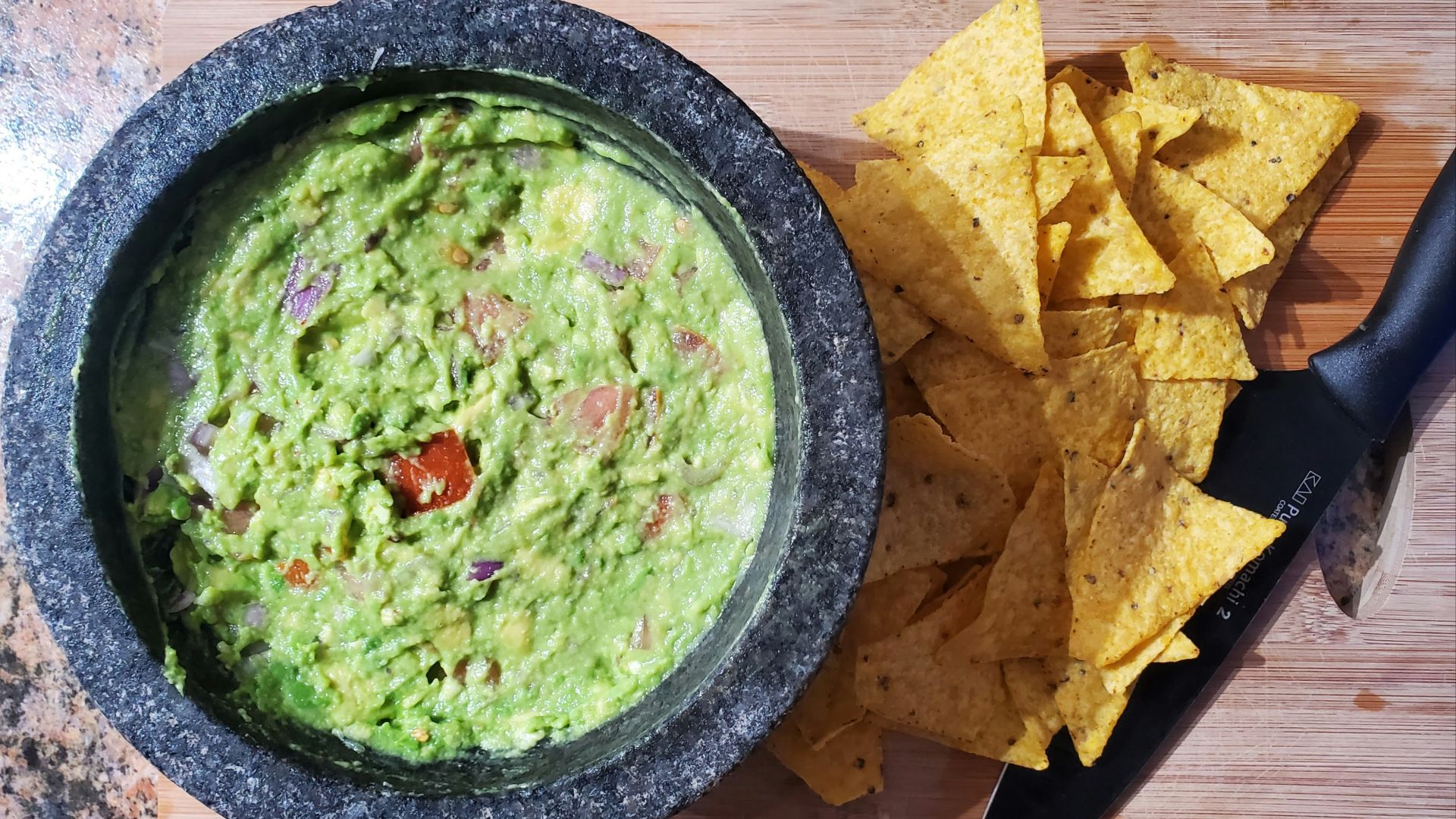 a bowl of guacamole next to a bowl of tortilla chips