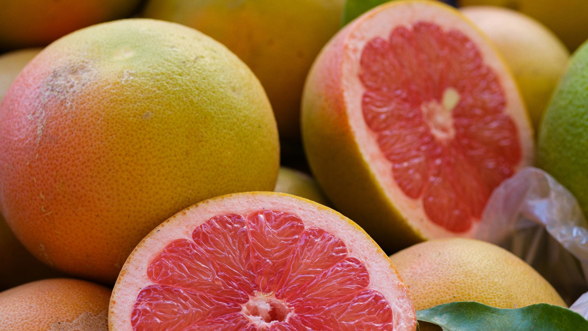 a pile of grapefruits with one cut in half