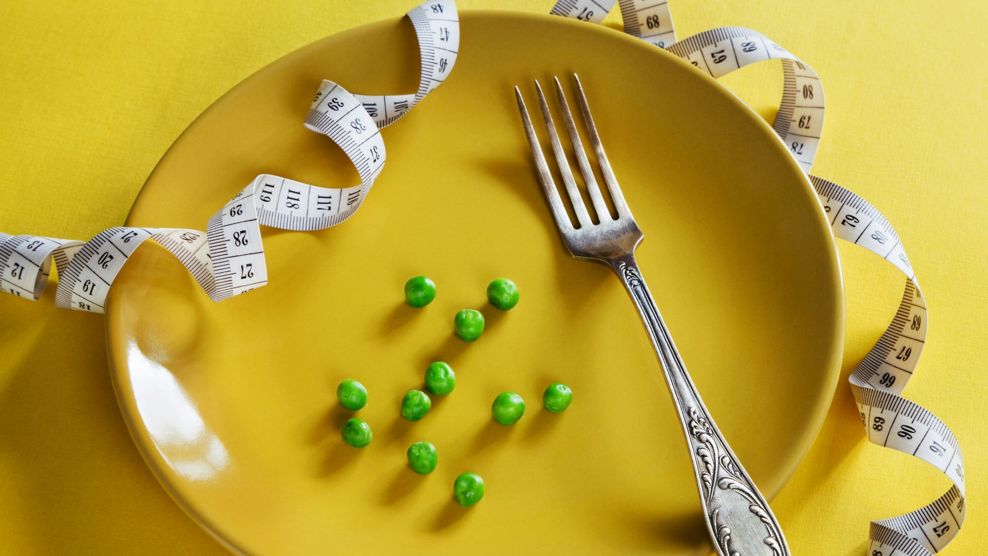 a plate with a fork, measuring tape and green peas