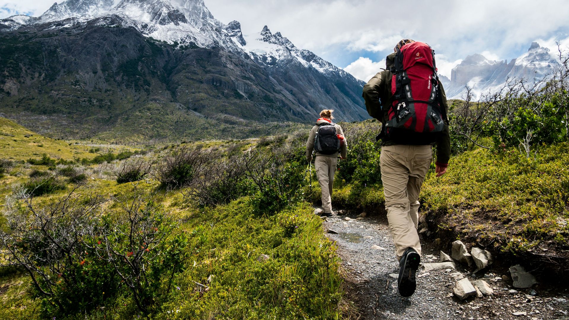 two person walking towards mountain covered with snow