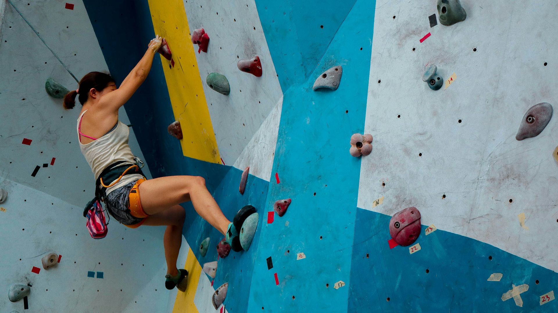 person in white tank top rock climbing