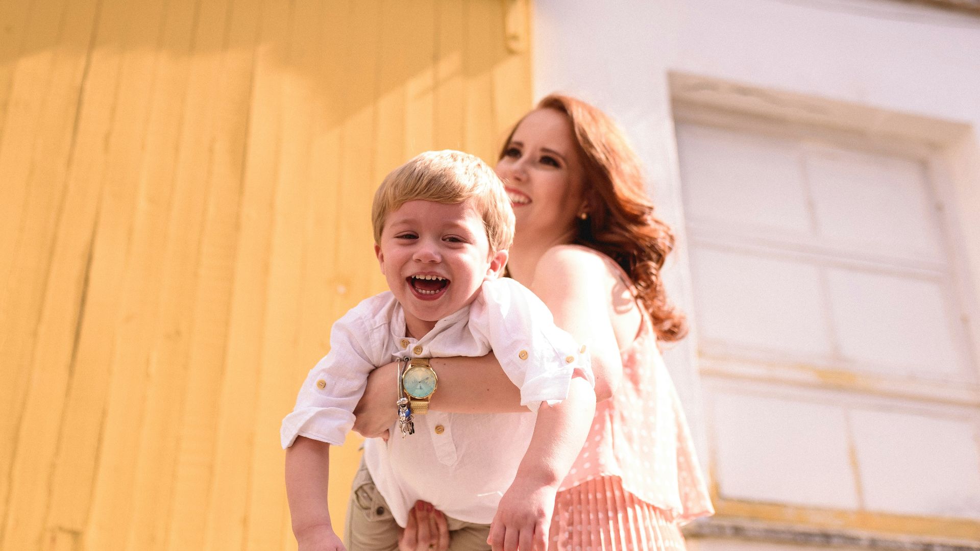 woman in blue and white plaid dress shirt carrying girl in white shirt
