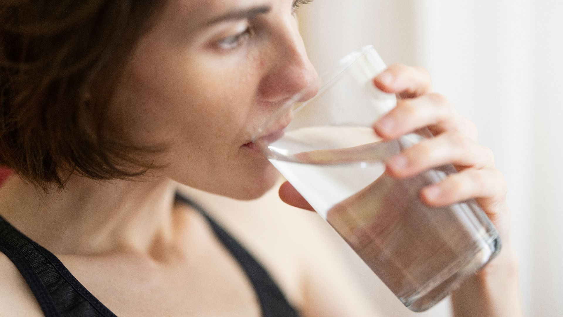 woman in black tank top drinking water