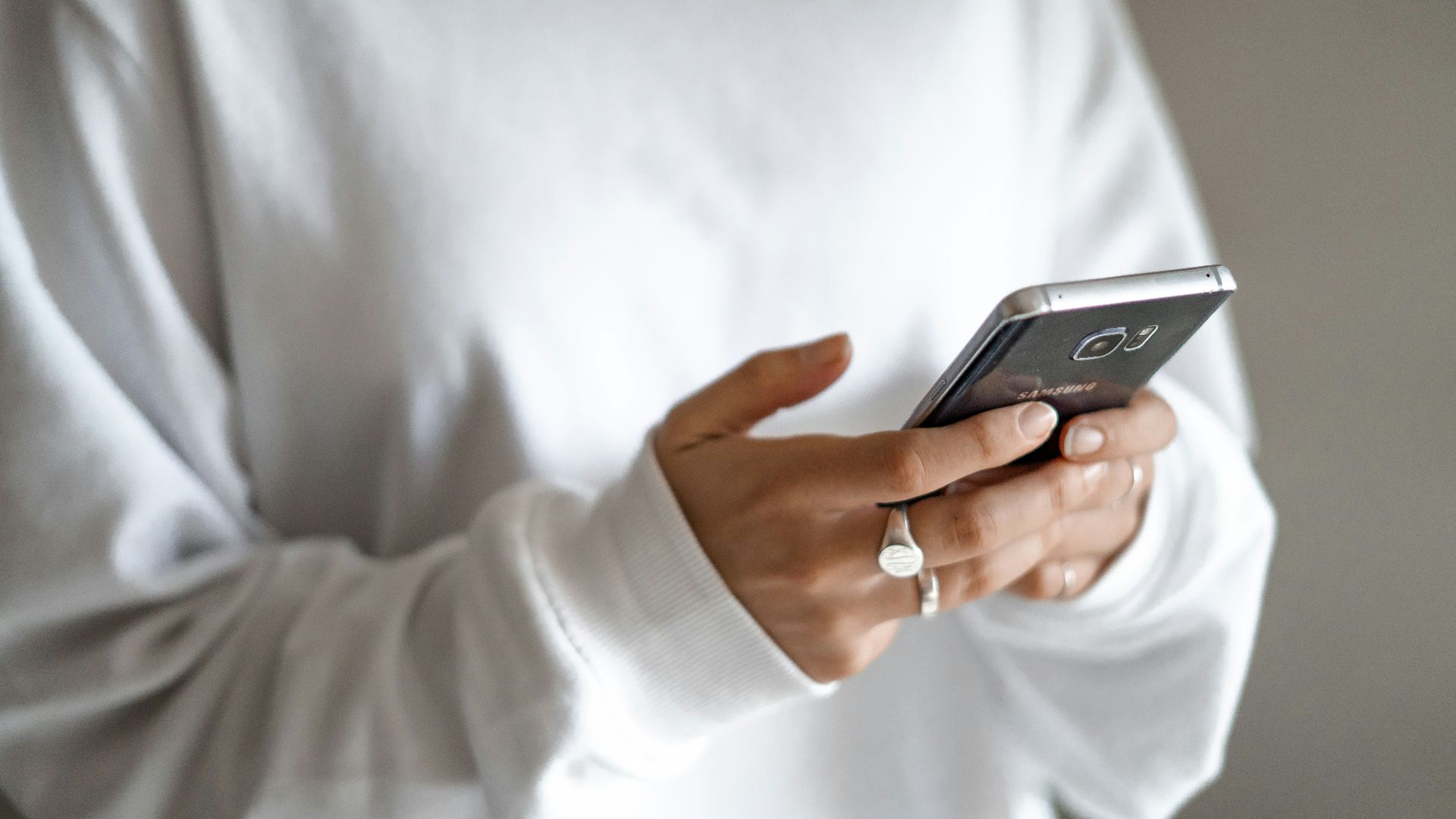 person in white long sleeve shirt holding black smartphone