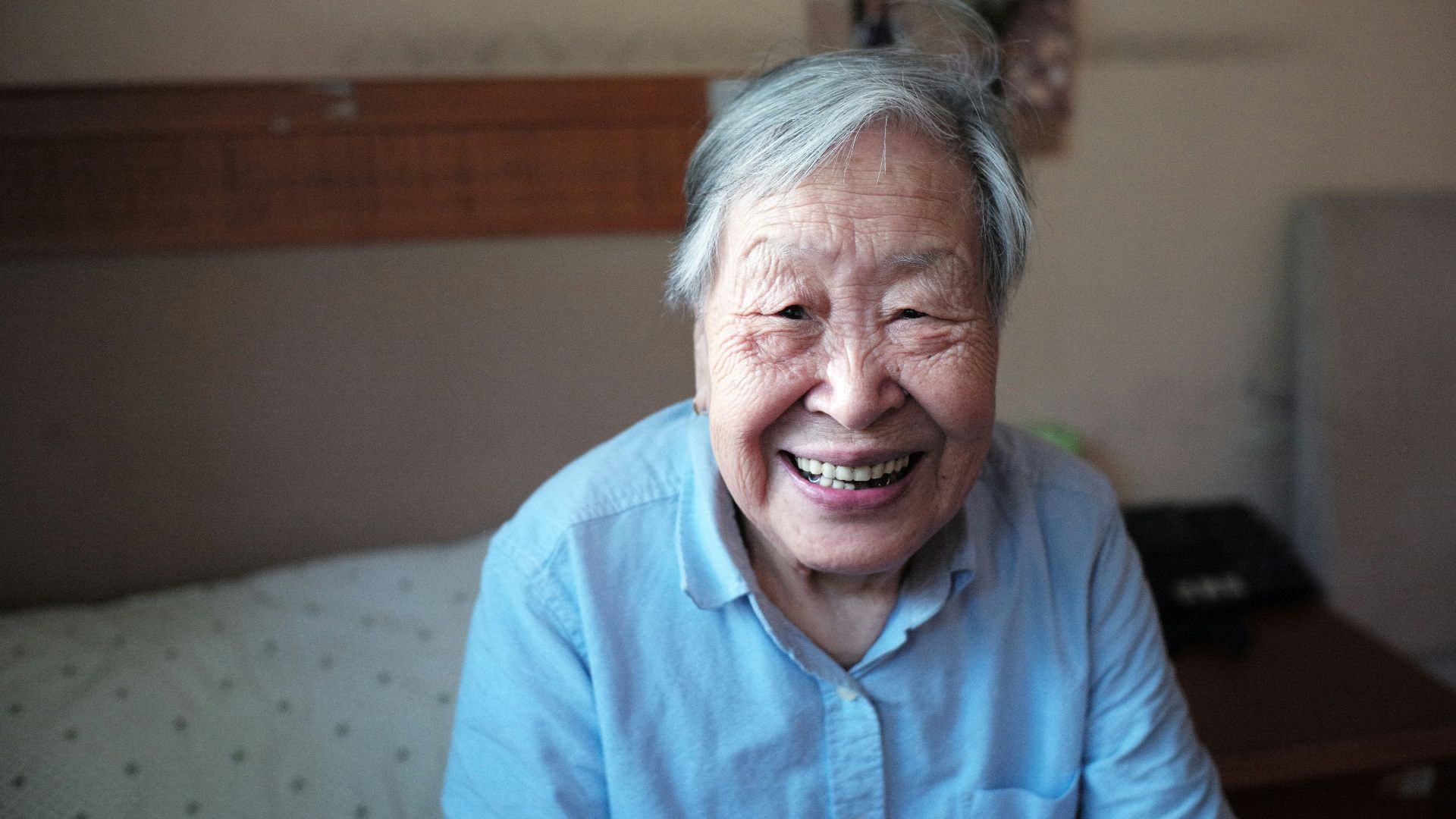 woman in blue button-down shirt smiling in front of camera
