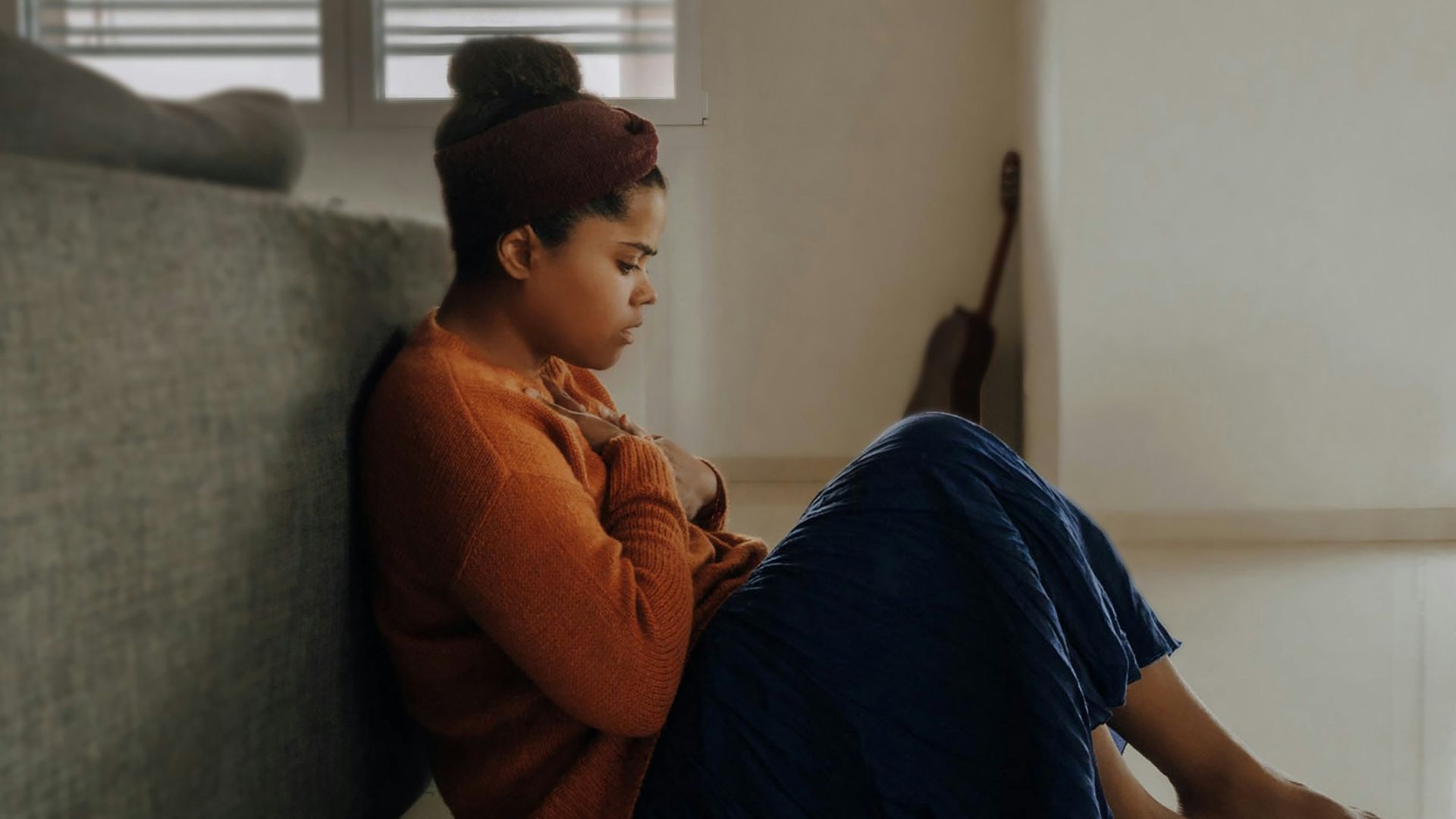 man in orange long sleeve shirt sitting on gray couch