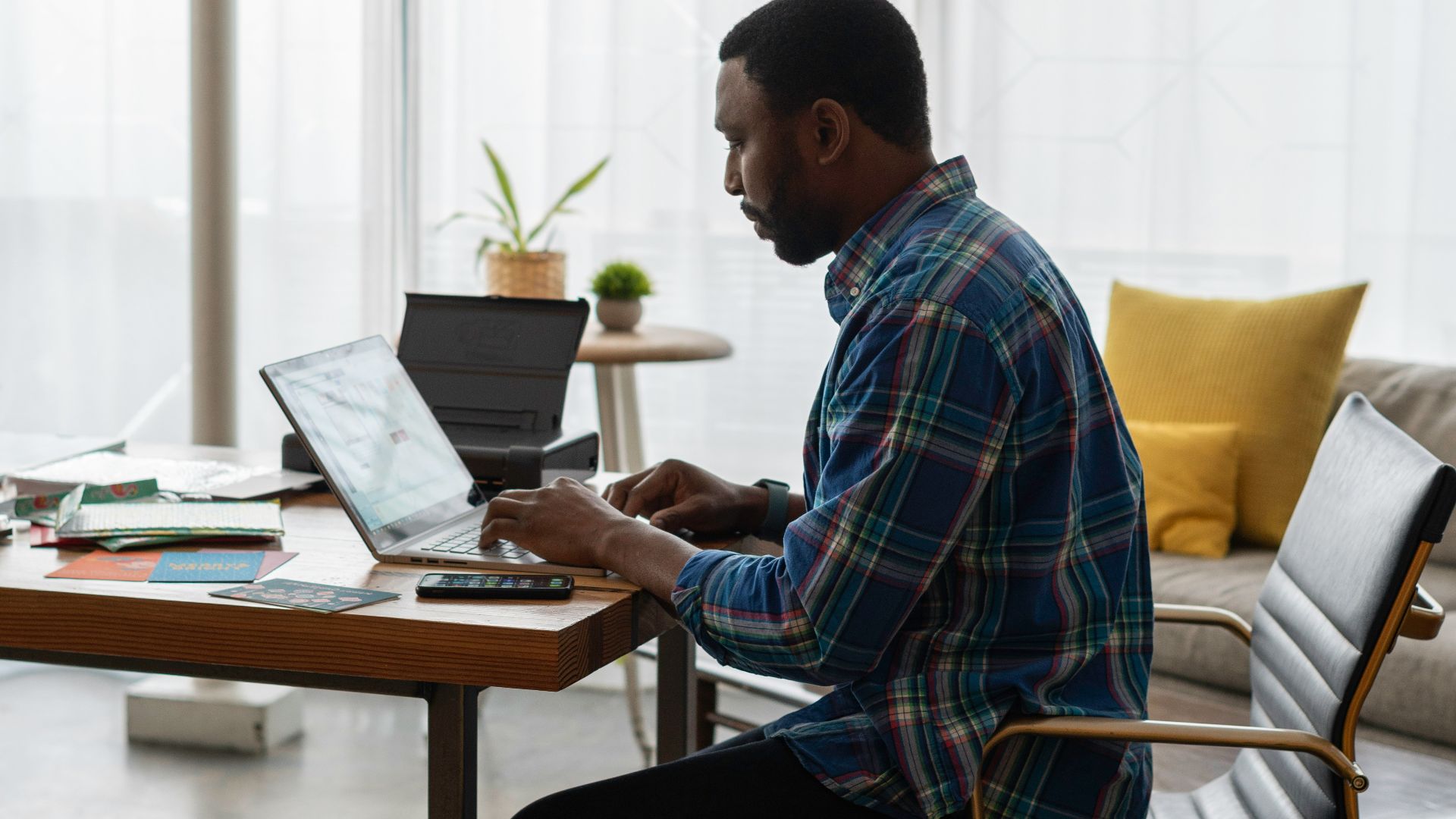 man in blue and white plaid dress shirt sitting on chair using laptop computer