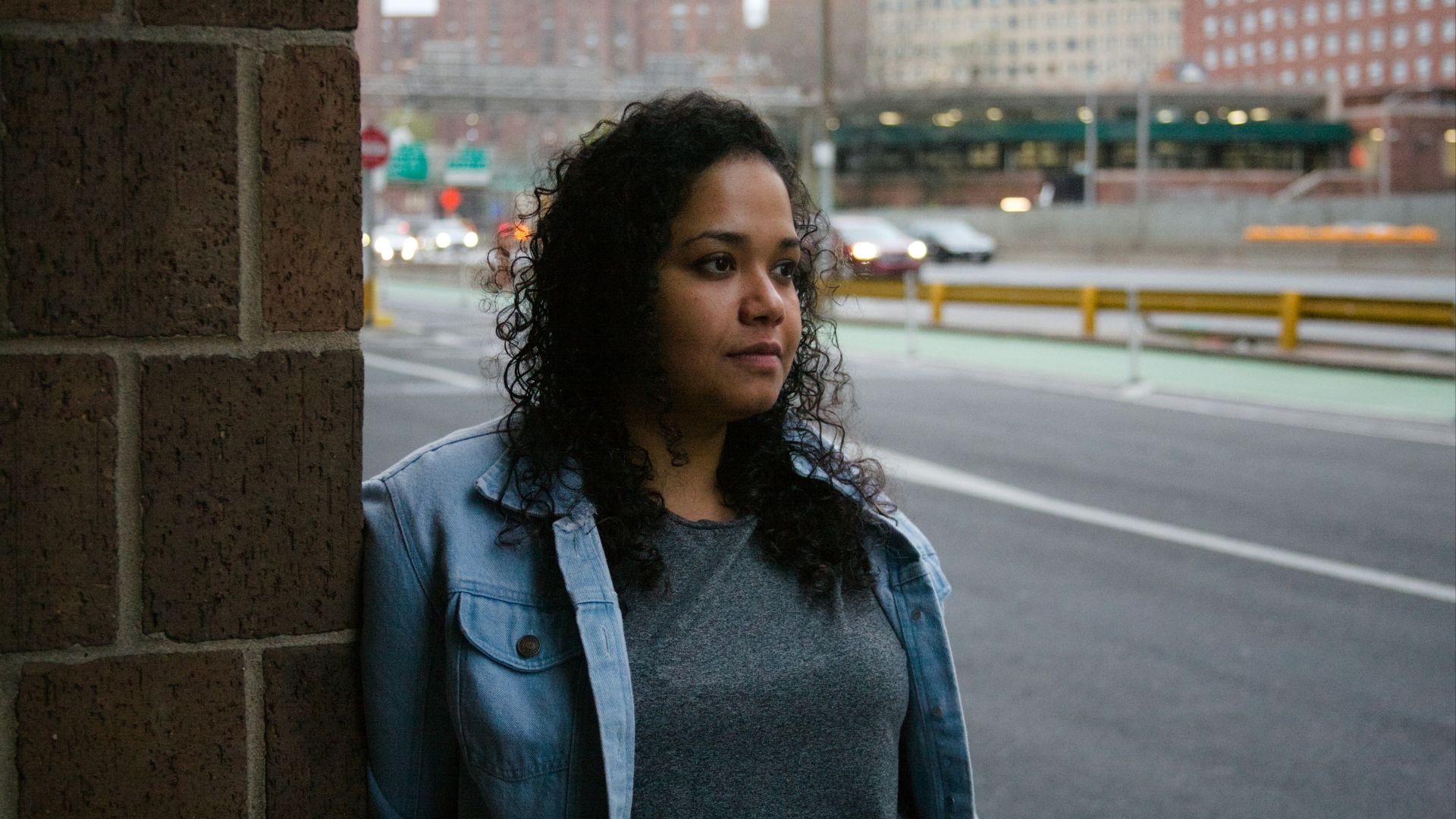 a woman standing next to a brick wall
