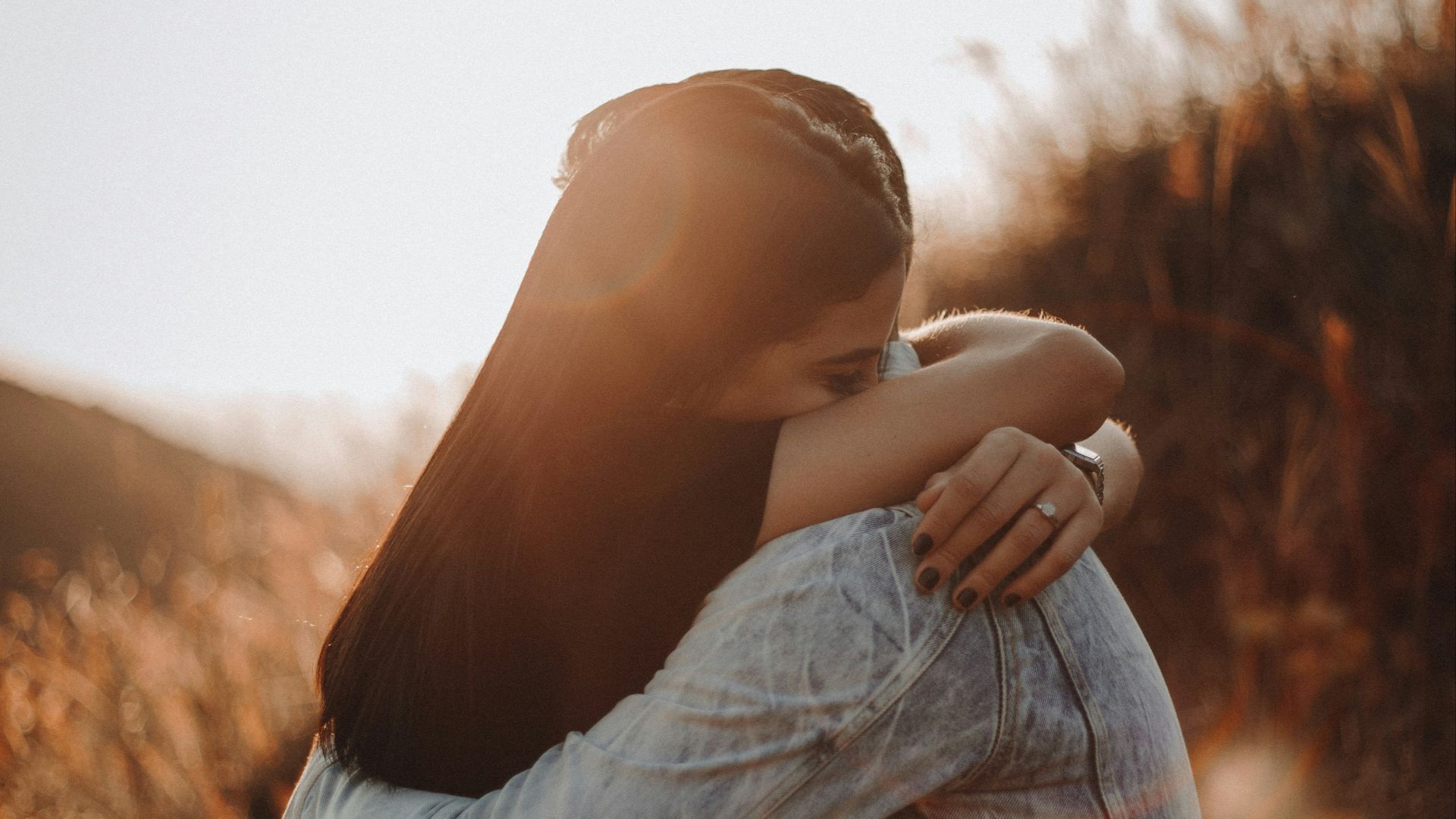 woman in black long sleeve shirt and blue denim jeans covering her face with her hand
