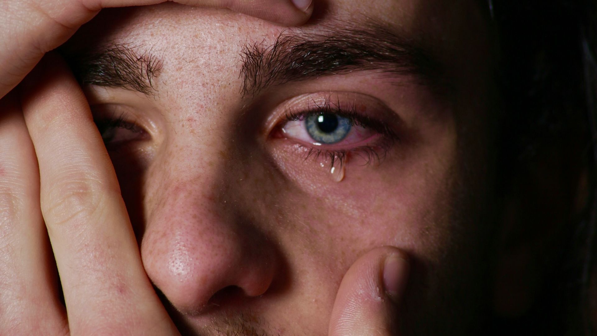 a man holding his hands to his face