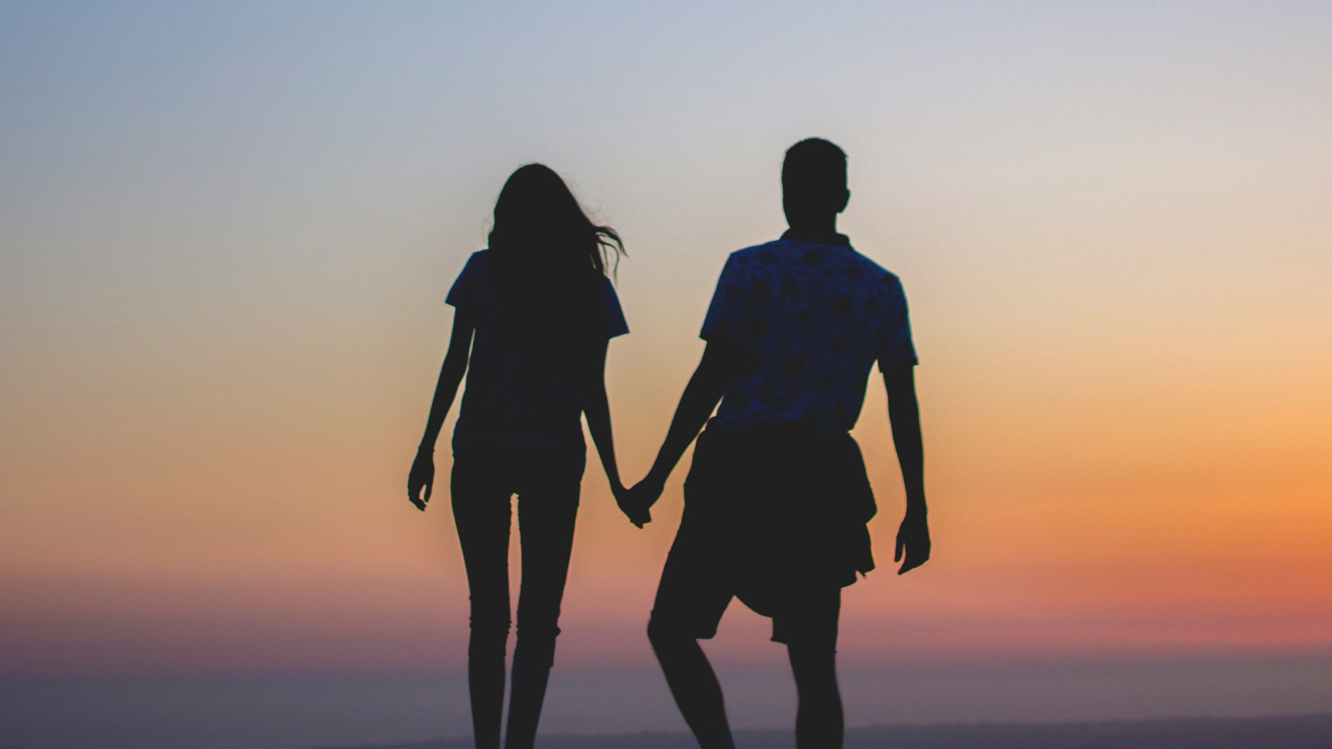 man and woman holding hands in silhouette photography