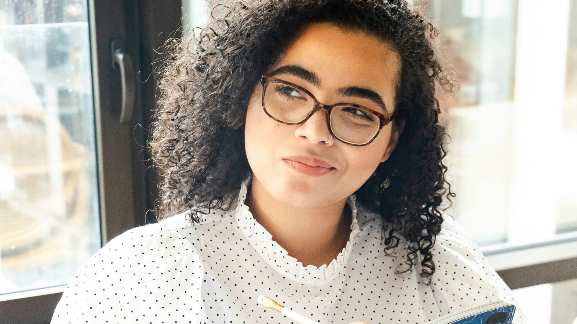 woman in white and black polka dot shirt holding blue and white book