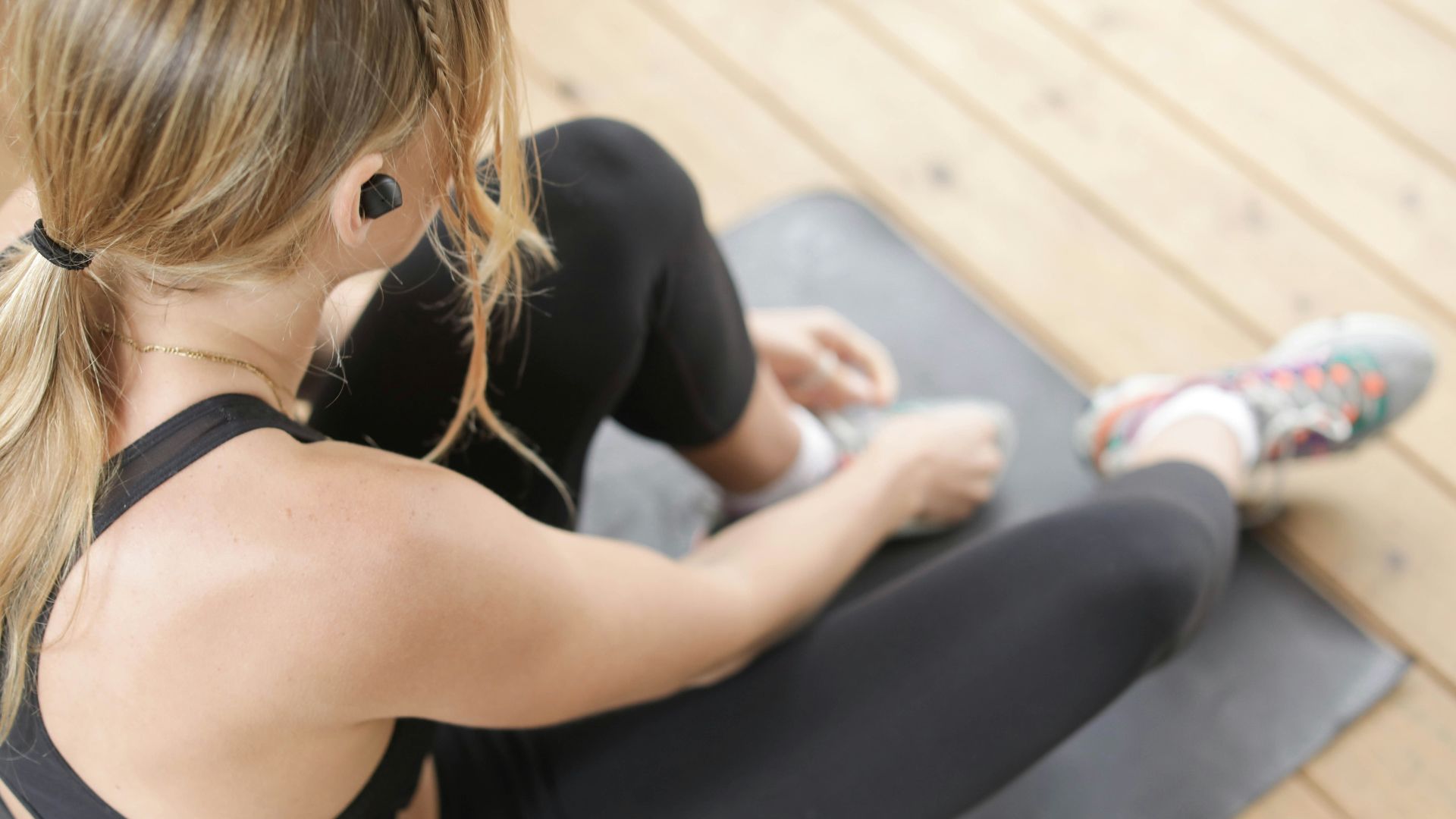woman in black tank top and black leggings sitting on gray bench