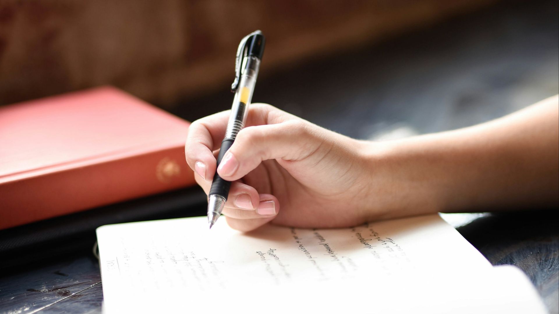 a person writing on a piece of paper with a pen