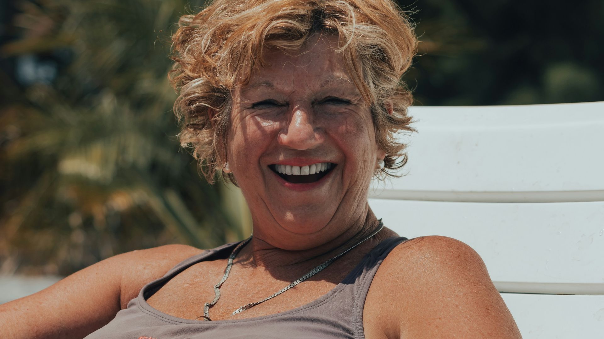 a woman sitting on a white bench smiling