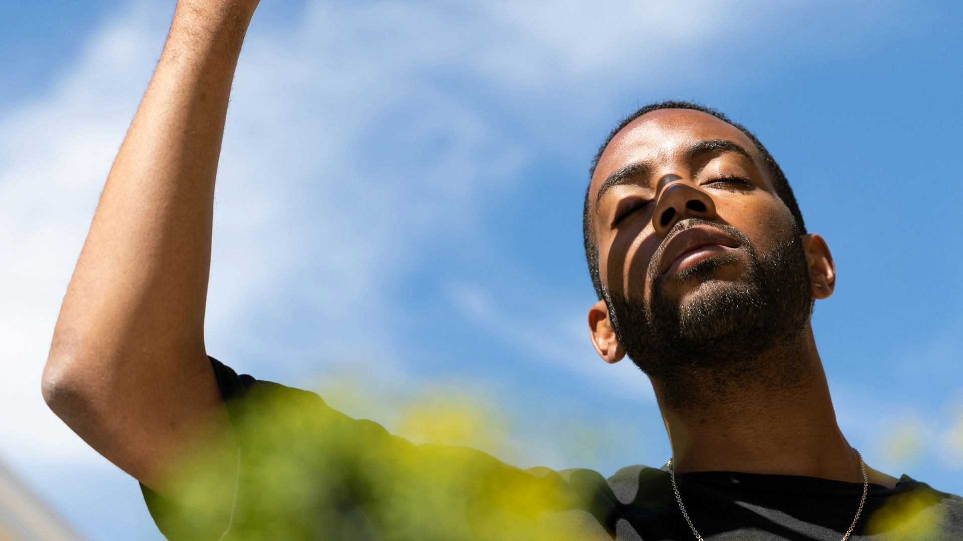 man in yellow and black crew neck shirt raising his right hand