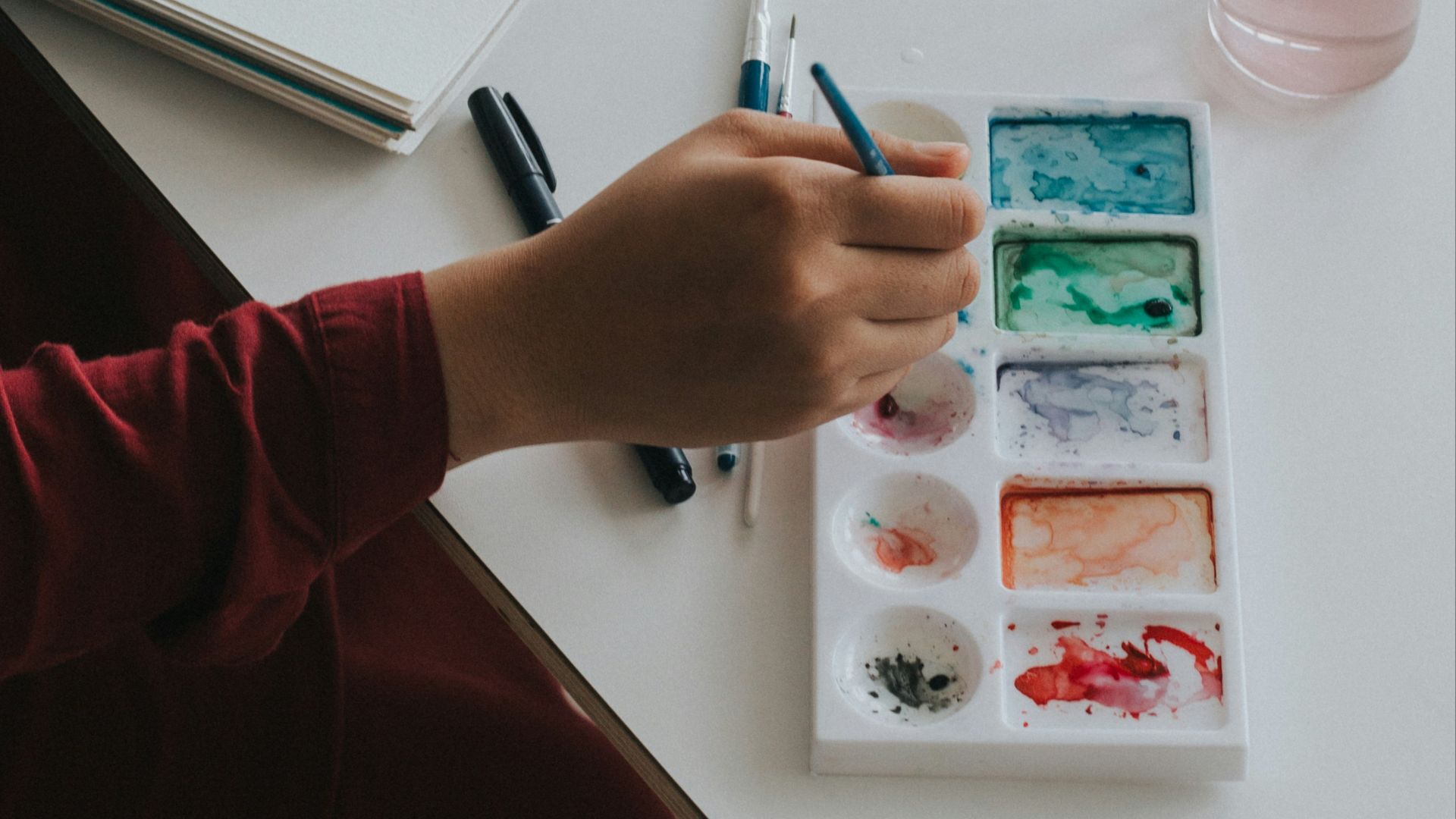 person dipping paintbrush on paint