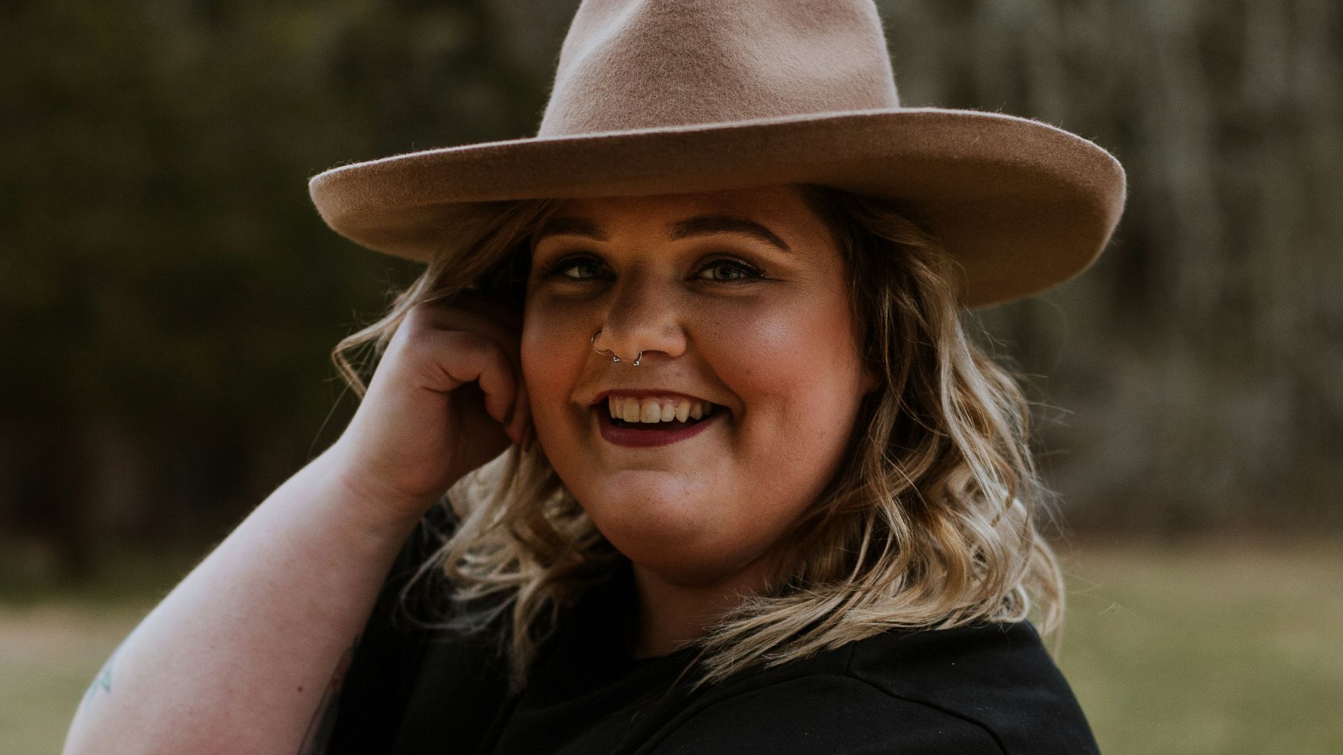 woman in black sleeveless dress wearing brown fedora hat