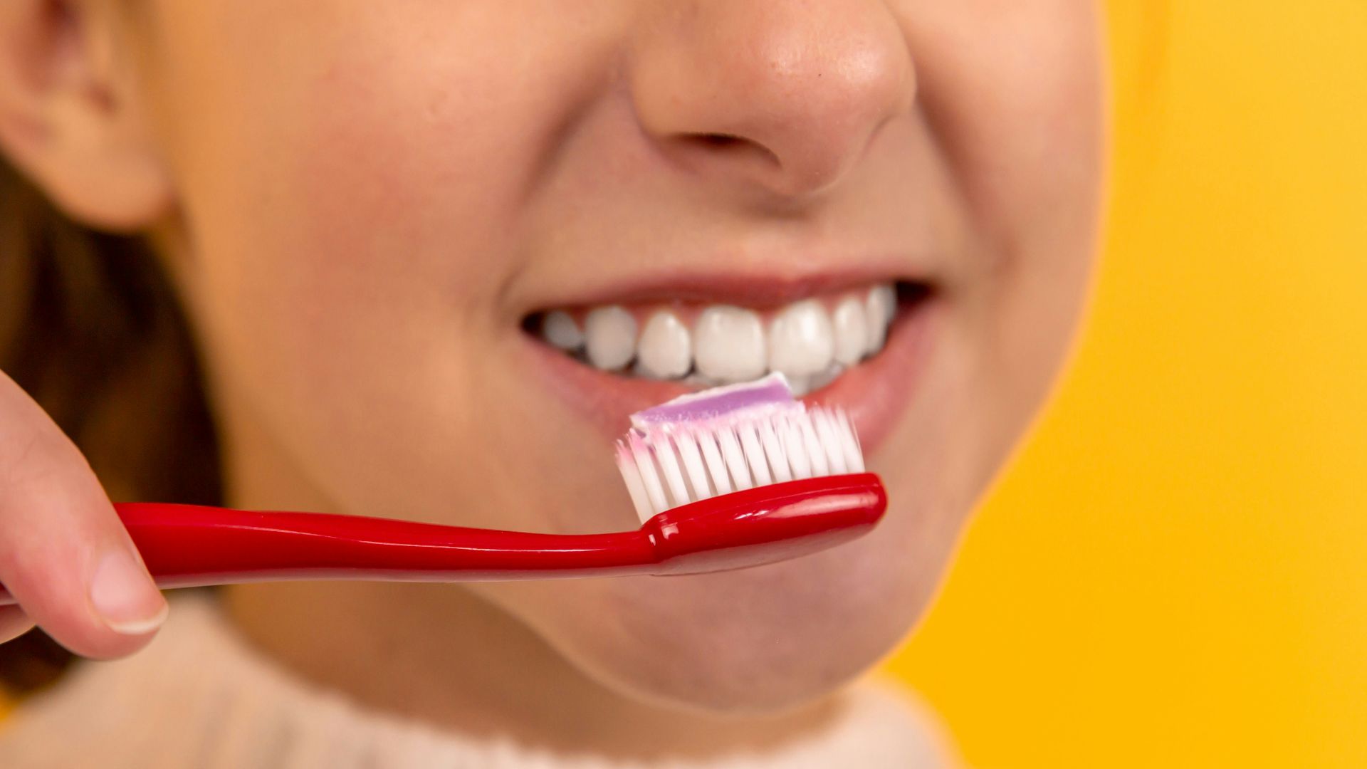 girl with red and white toothbrush in mouth