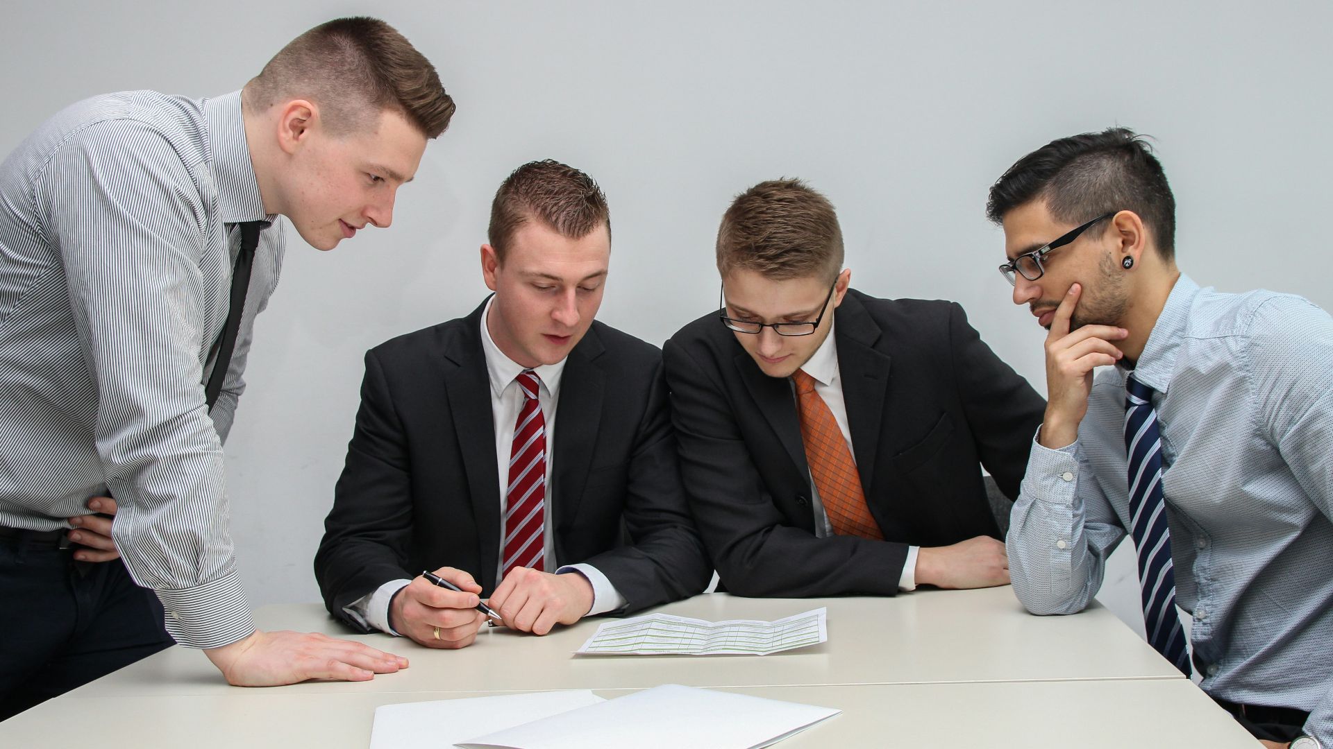 four men looking to the paper on table