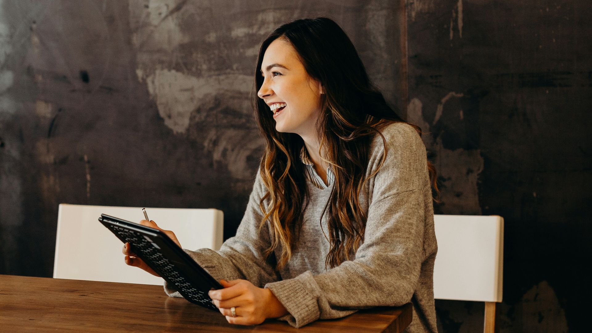 woman sitting around table holding tablet