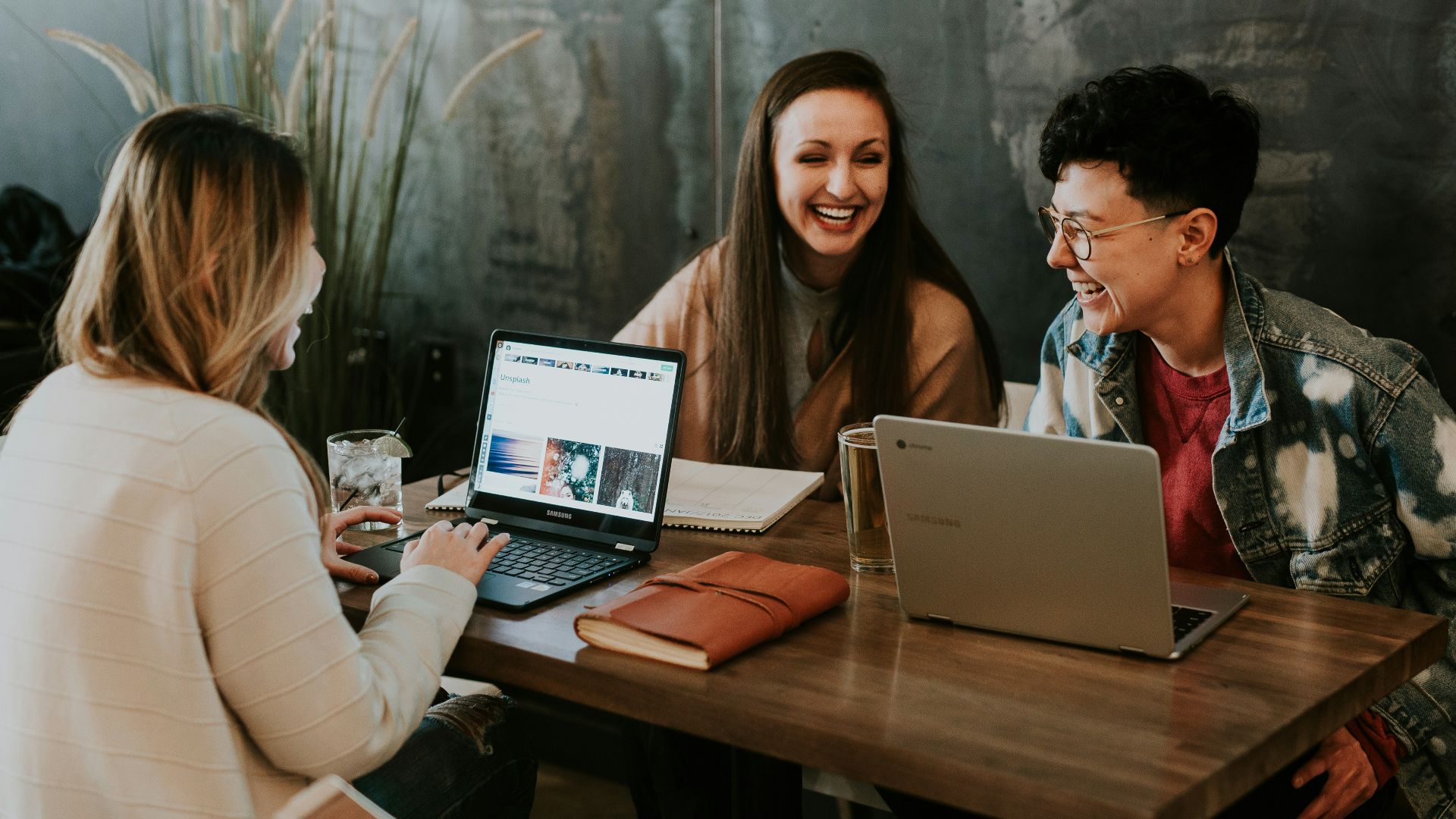 three people sitting in front of table laughing together