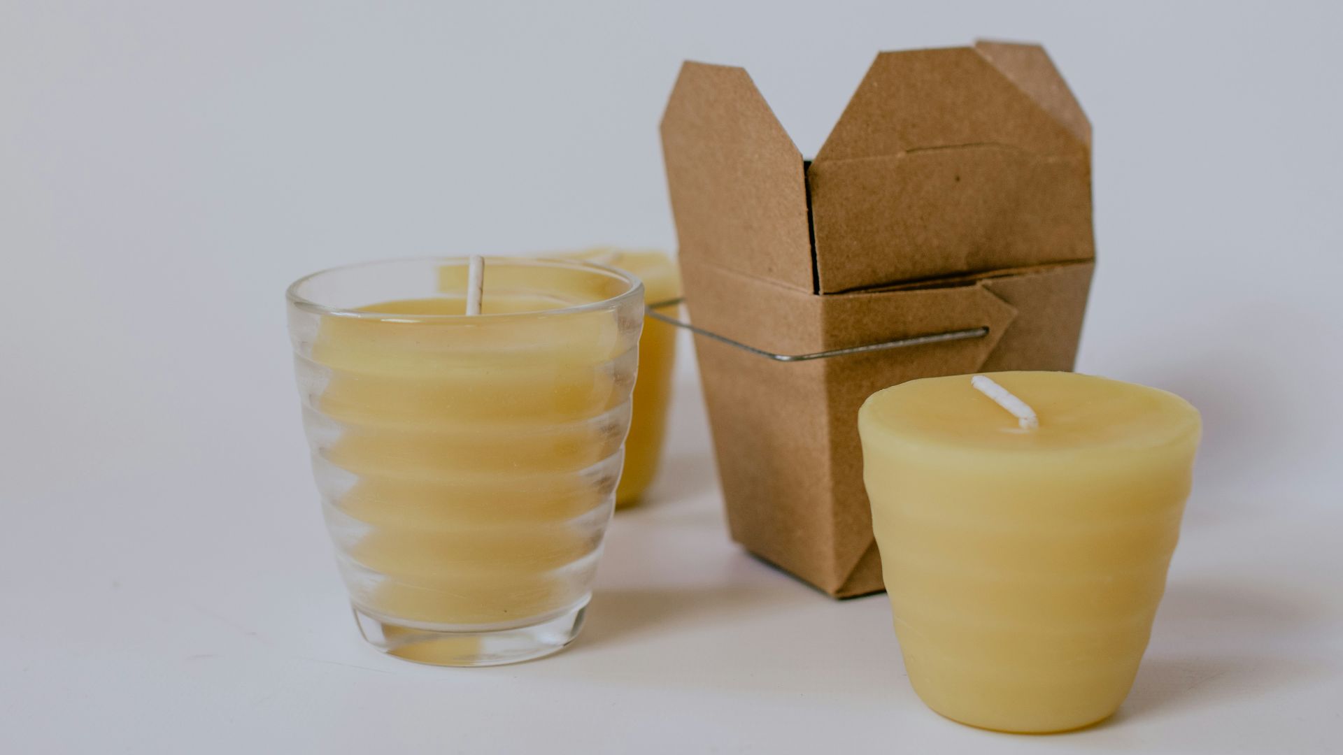 three yellow pillar candles near small brown box