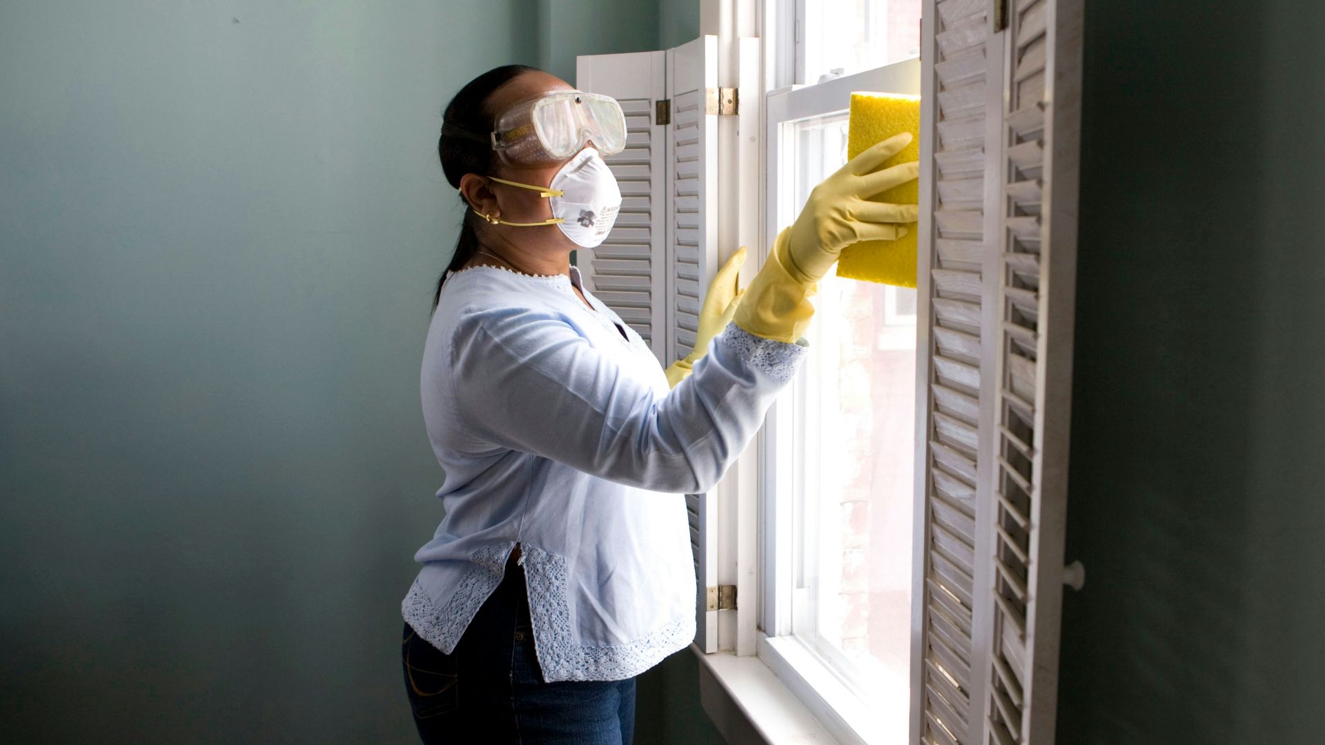 woman in white long sleeve shirt and blue denim jeans standing beside white wooden framed glass