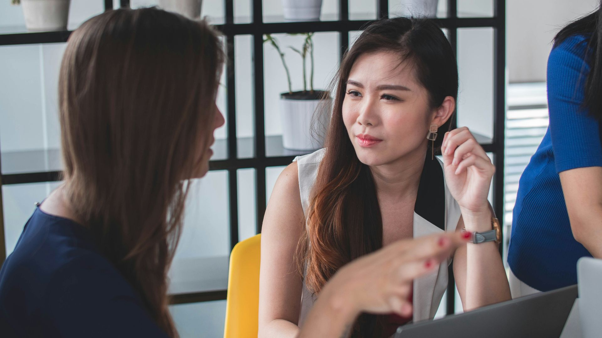 woman sitting on yellow armless chair near gray laptop computer