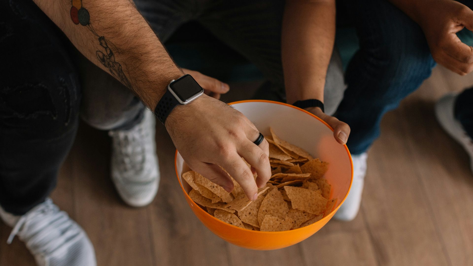 person holding orange bowl with potato chips