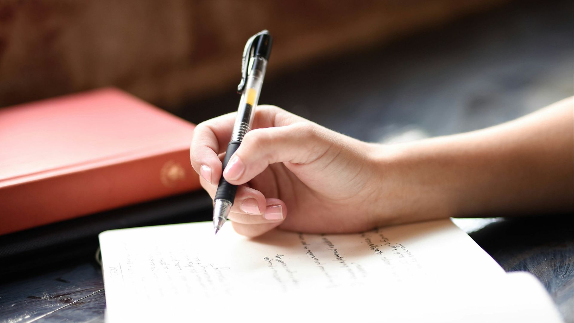 a person writing on a piece of paper with a pen